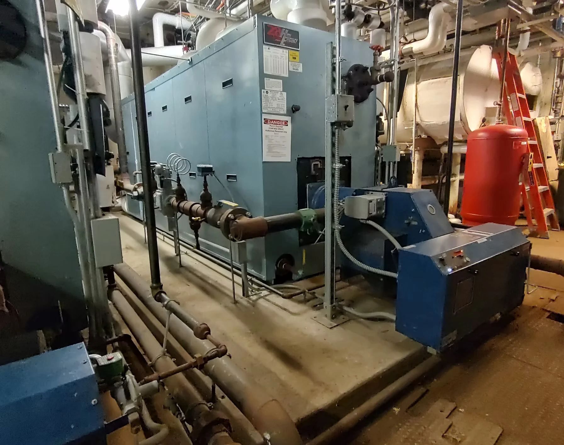 A picture of an industrial mechanical room, featuring large pipes and machines